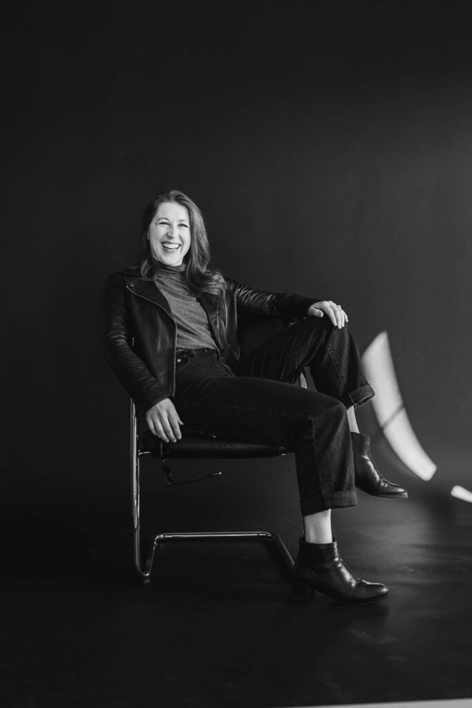 A black and white photo of a woman sitting sideways in a chair