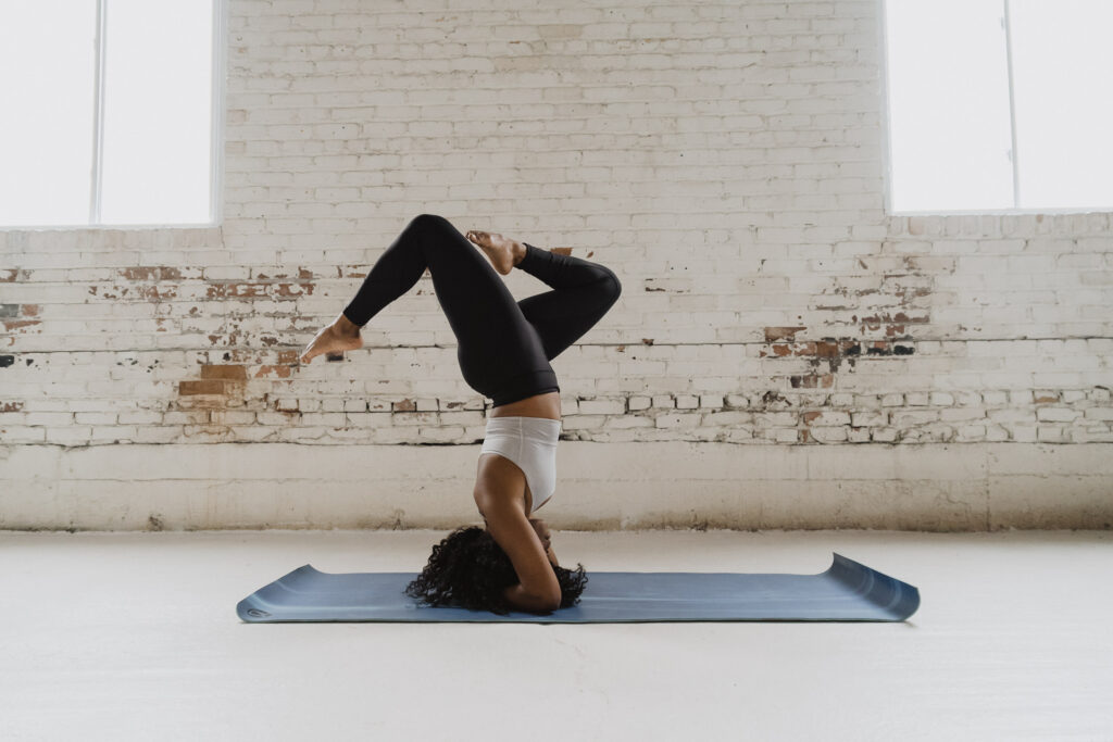 A woman does a headstand pose on a yoga mat during a boudoir studio seession