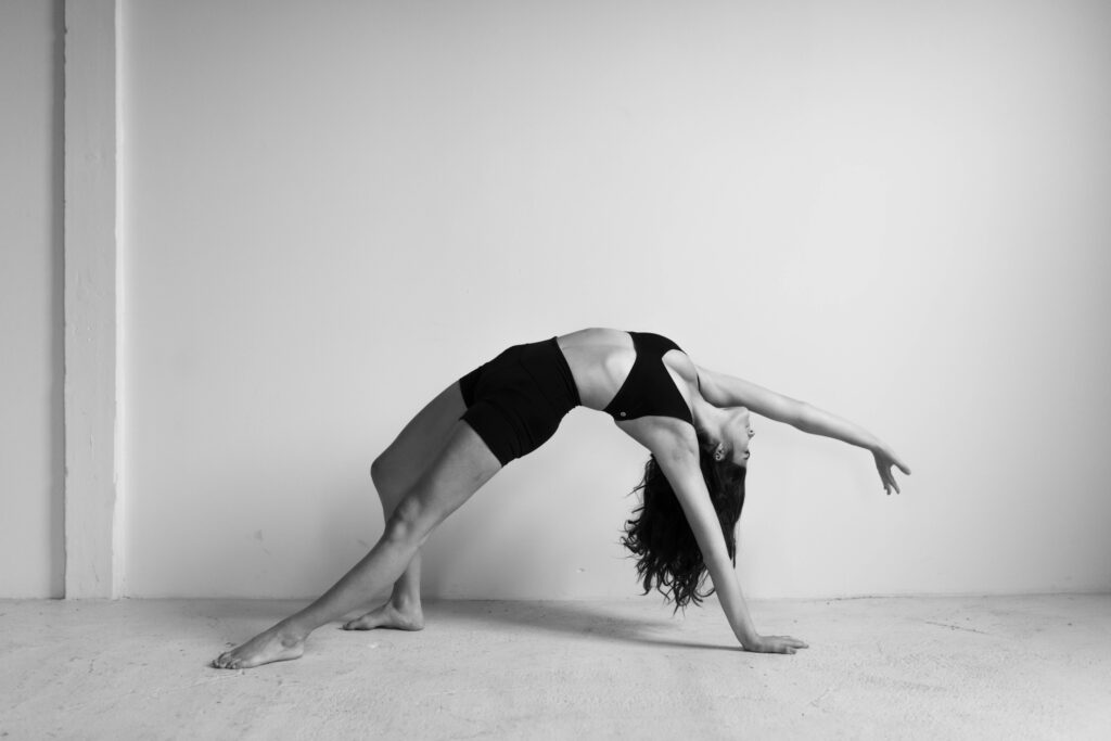 A woman artistically poses in shorts and a bra for a boudoir session