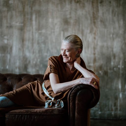 An older woman poses on a couch for a boudoir session